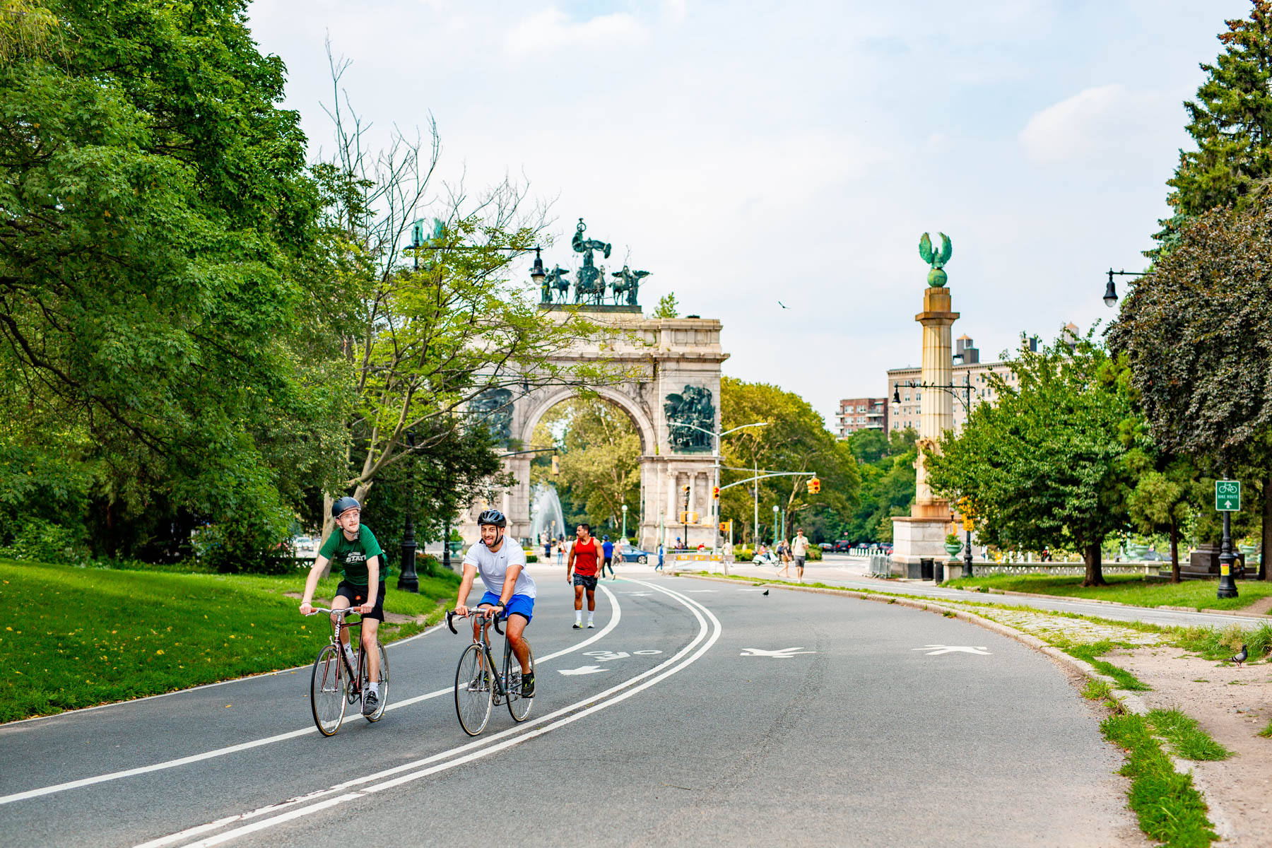 People biking in Prospect Park with a view of the Soldiers and Sailors Memorial Arch in the background in Park Slope, one of the best New York City neighborhoods to live in