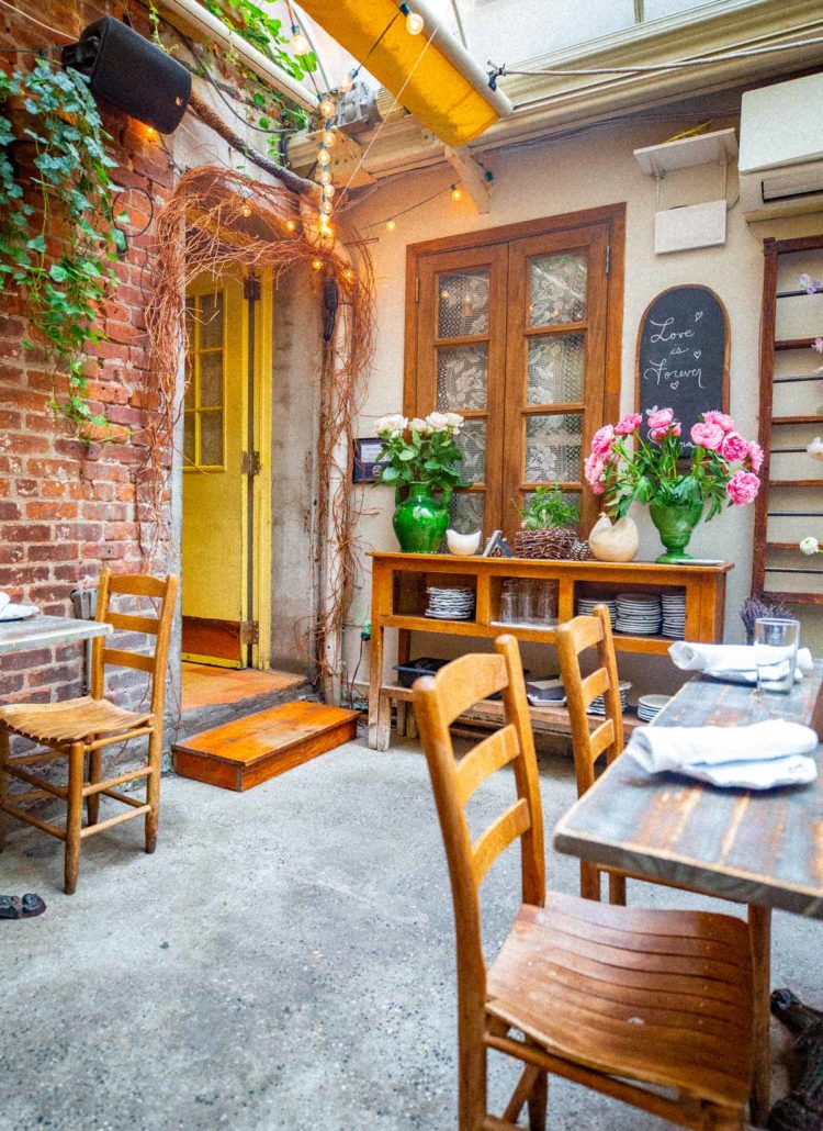 Rustic chairs and table with a Tuscan Italian vibe at Palma in the West Village. Green vase with fresh flowers and vintage dishes on display at one of the most romantic restaurants in NYC