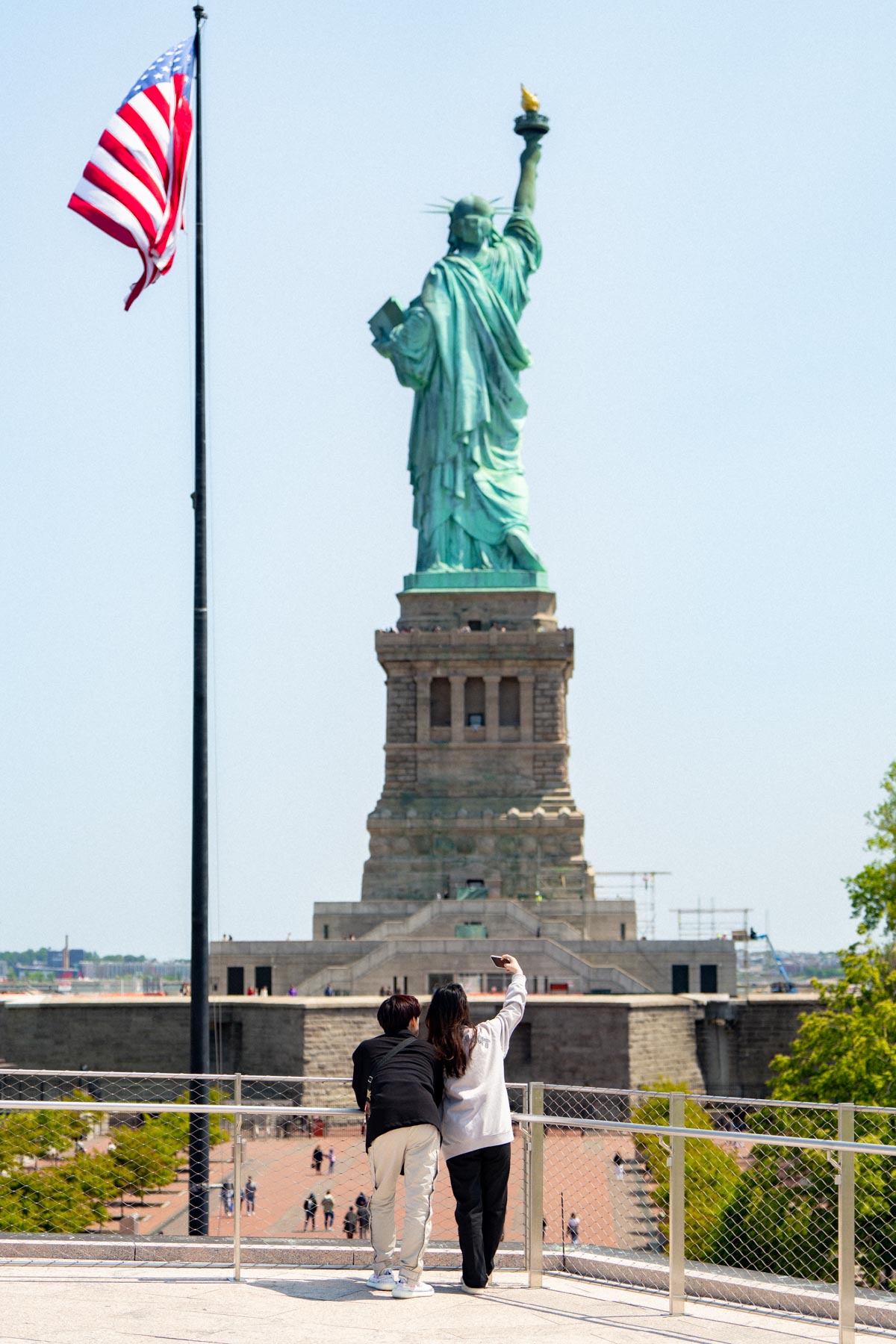 Couple standing in front of the Statue of Liberty on Liberty Island, visiting the Statue of Liberty