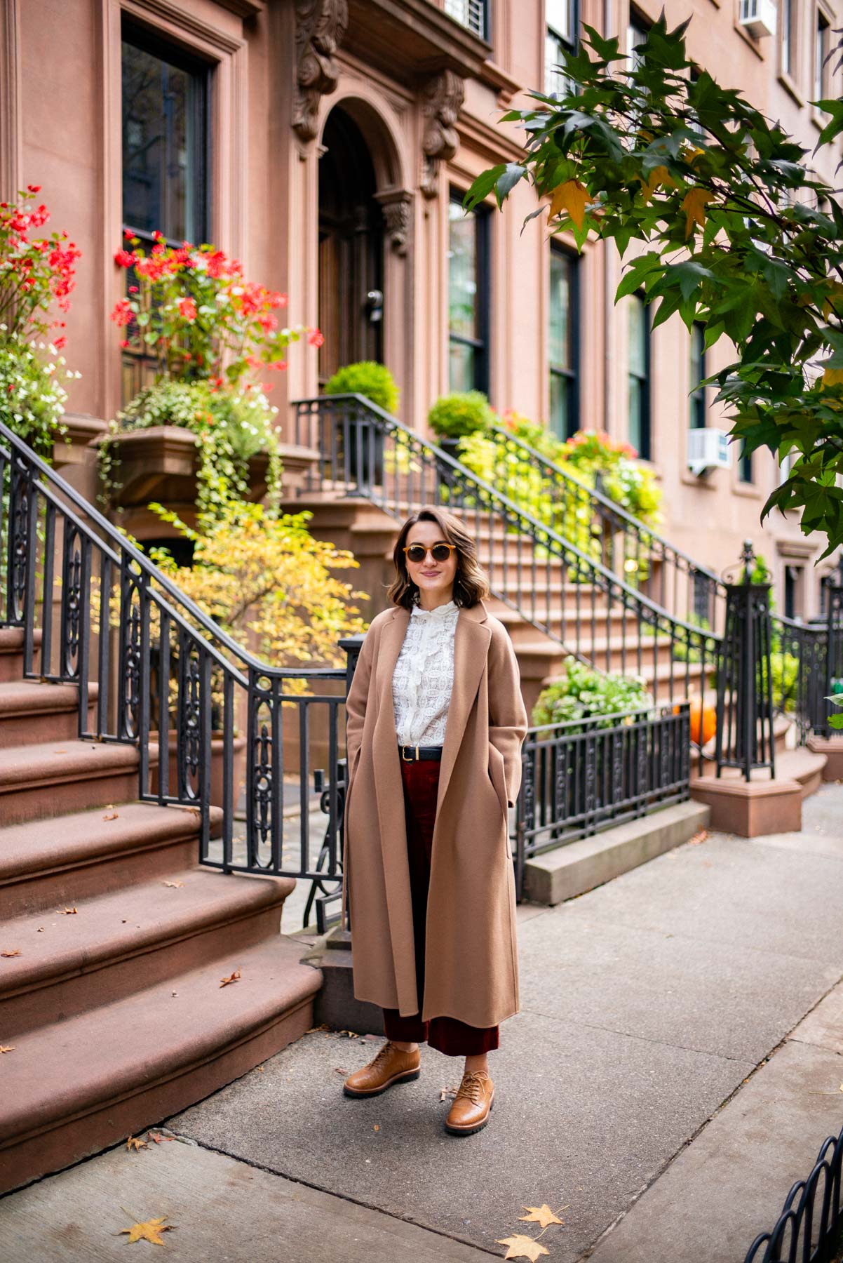Fashionable woman wearing a long coat standing in front of Brownstone stoops in Brooklyn Heights, one of the Best neighborhoods to live in New York City