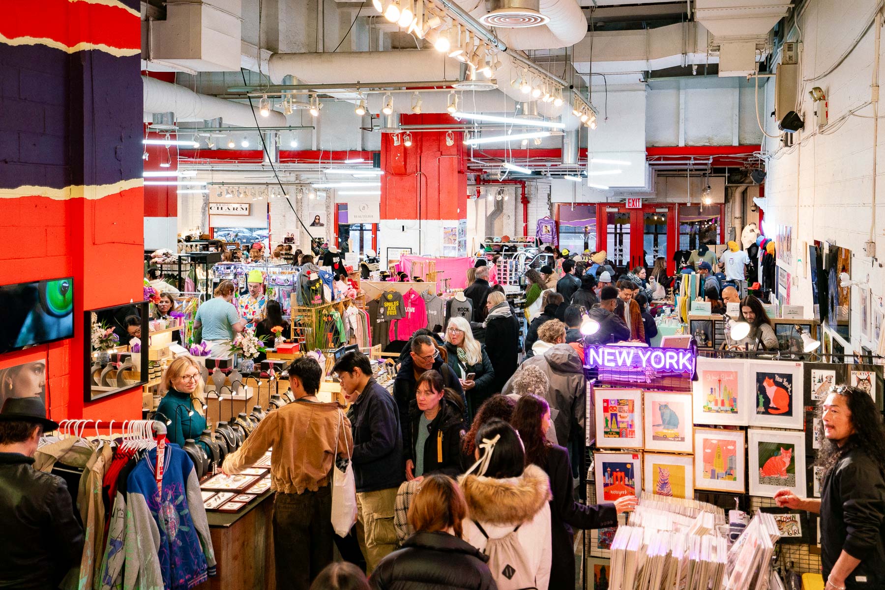 People shop the many vendors, including painters, clothing designers, and photographers, at Artists & Fleas Chelsea Market, one of the best gift shops for souvenirs in NYC
