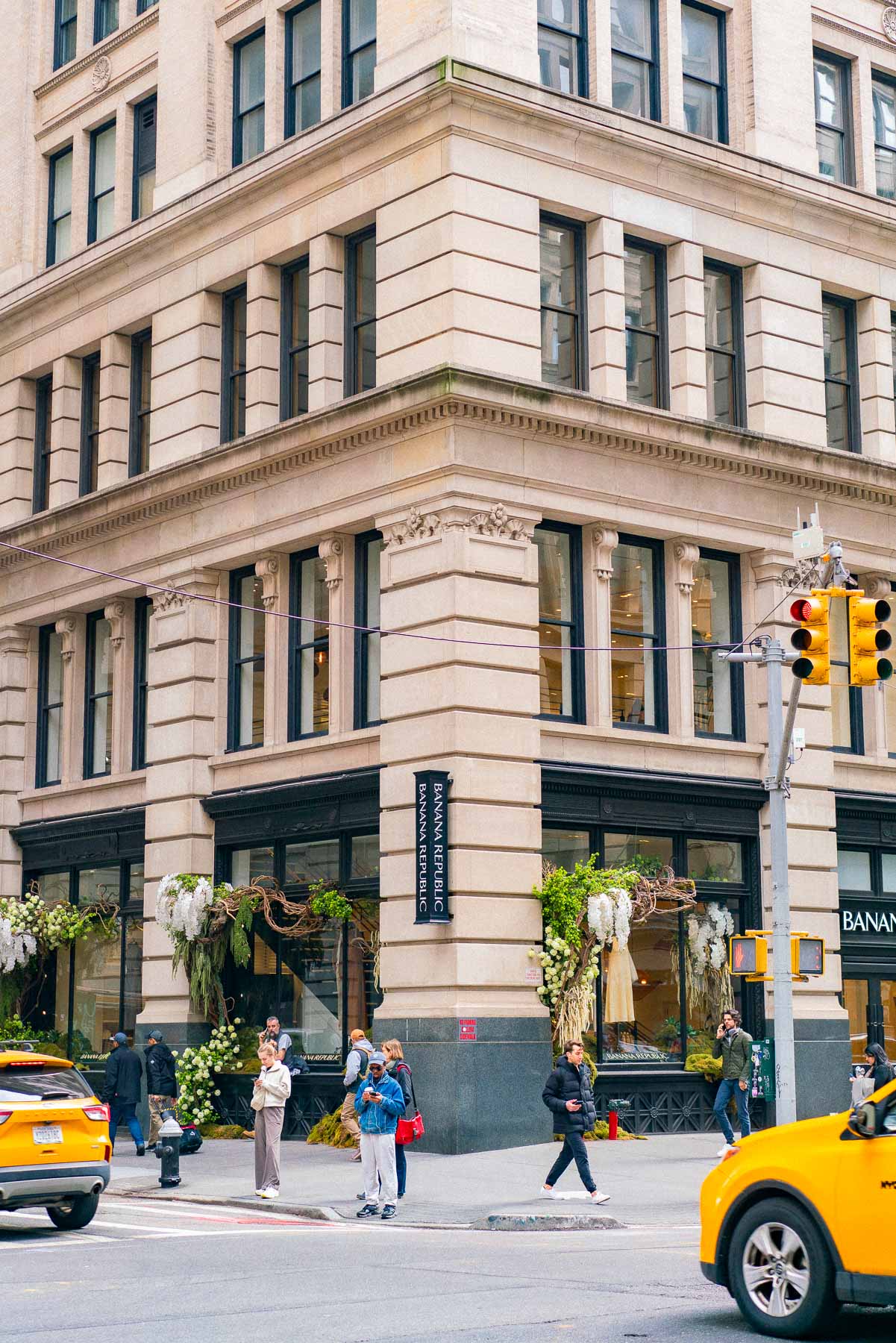 People shopping at Banana Republic in Union Square/ Flatiron District of NYC. People crossing the street with yellow taxis waiting at the street lights