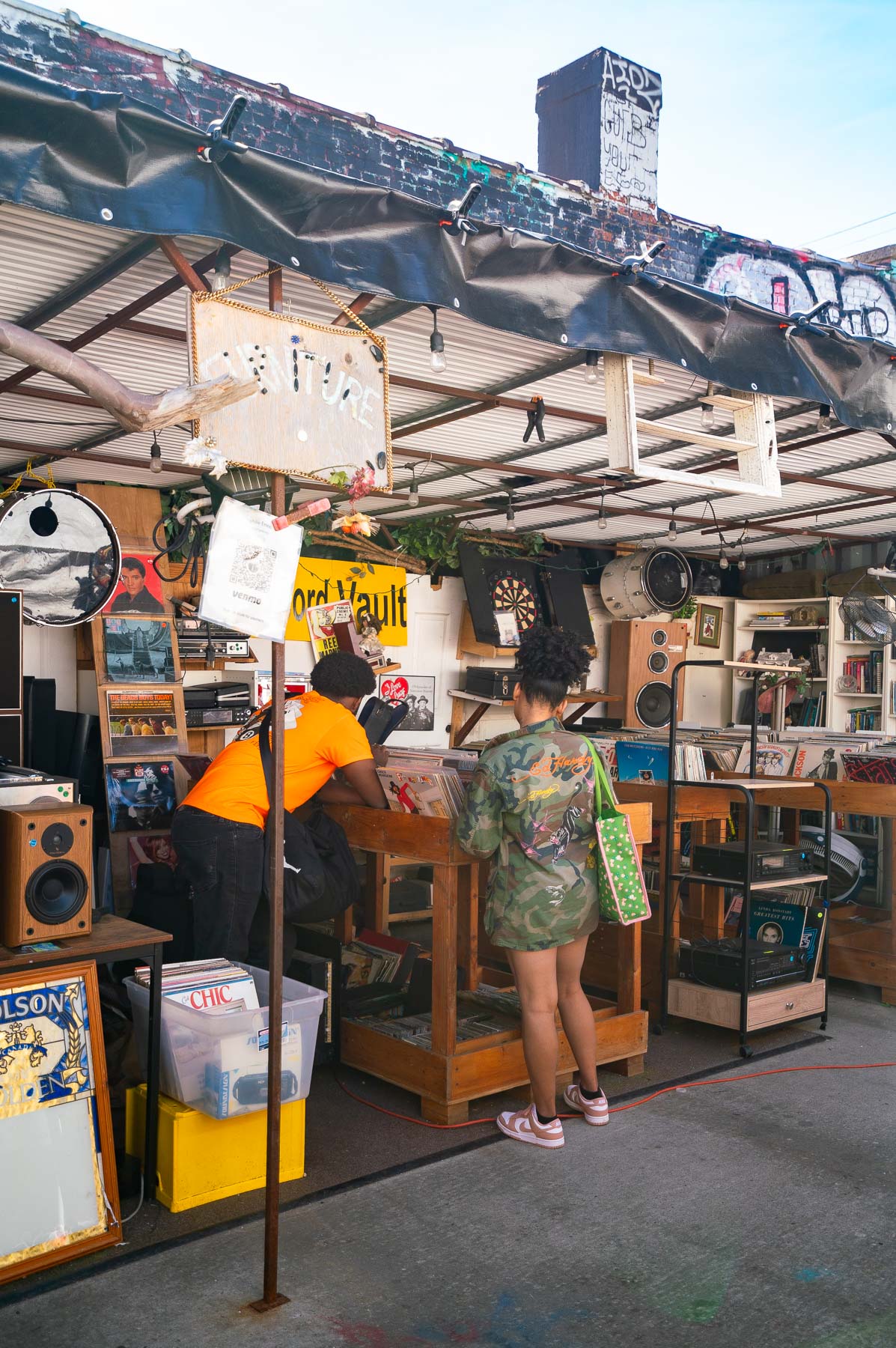 Young couple going through records under a covered awning at the Bushwick Flea Market, best neighborhoods Brooklyn